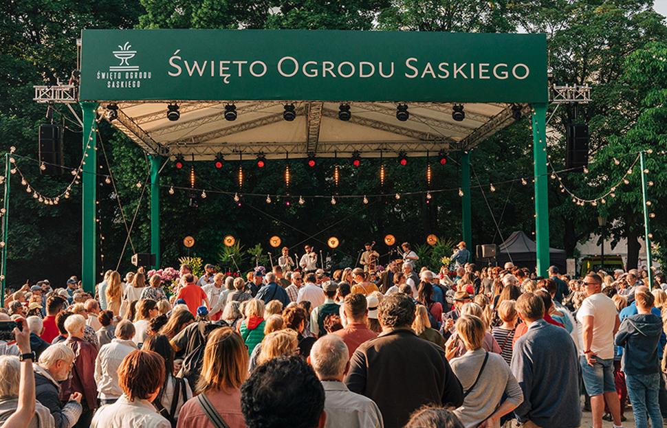 Uczestnicy 2. edycji Święta Ogrodu Saskiego na tle sceny z nazwą wydarzenia na zielonym banerze na górze sceny.